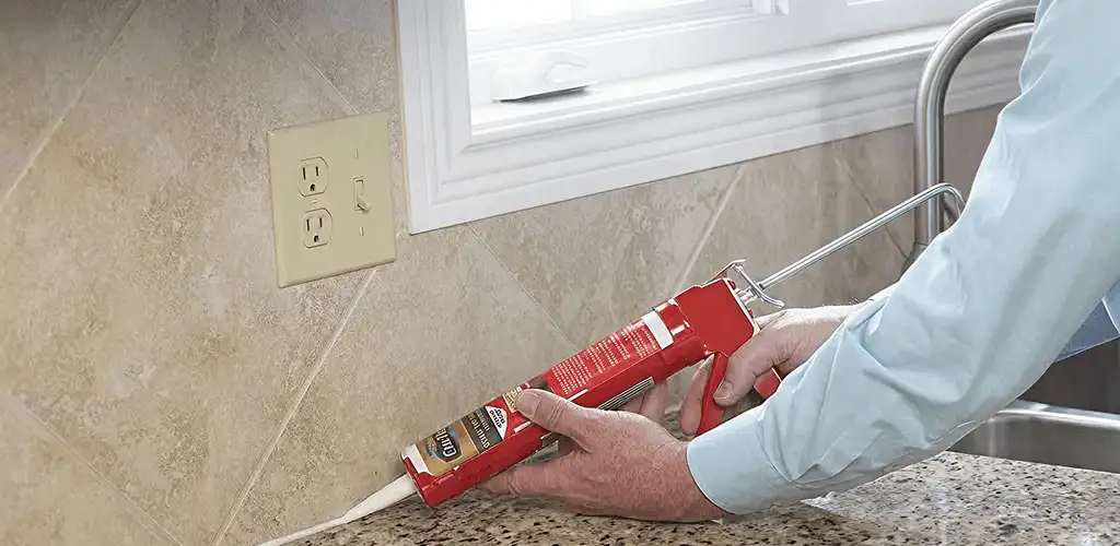 Handyman applying caulk along a kitchen backsplash and countertop seam in Shreveport, LA