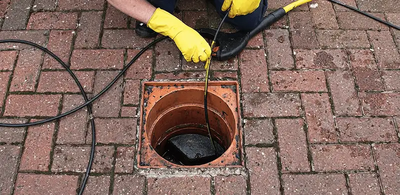 Drain cleaning technician using a drain snake to clear a clogged drain in Shreveport, LA