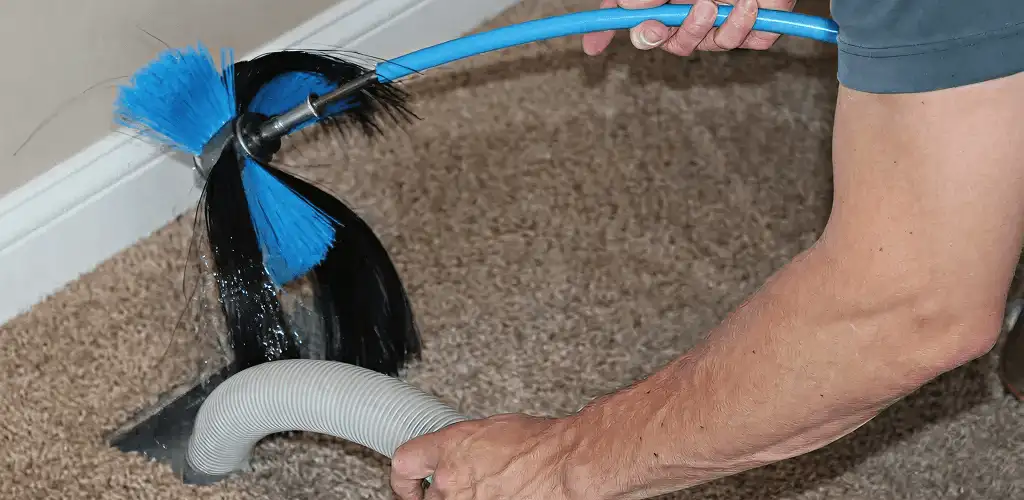 Dryer vent cleaning technician brushing lint from a vent line in Shreveport, LA
