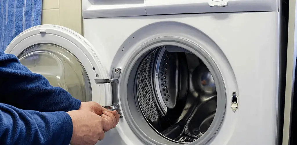 Washing machine repair handyman checking a front-load washer door and latch in Shreveport, LA