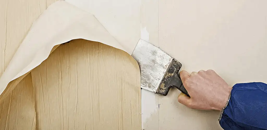 Handyman removing wallpaper with a scraper for wall preparation in Shreveport, LA