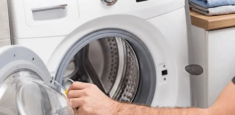 Handyman repairing a front-load washing machine and inspecting the drum in Shreveport, LA