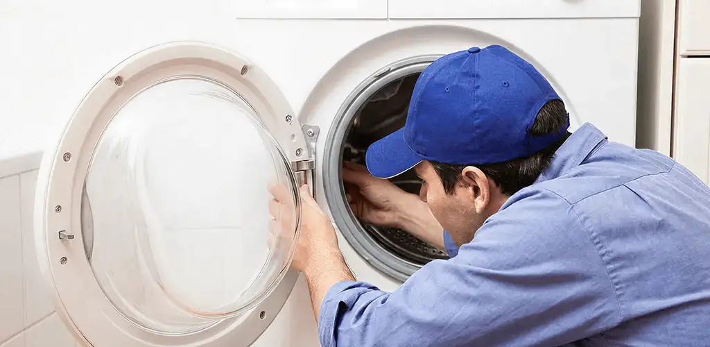Washing machine repair handyman inspecting a front-load washer drum in Shreveport, LA