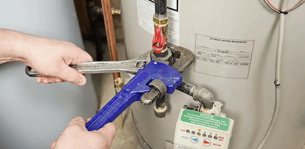 Water heater repair technician tightening the shutoff valve and supply line in Shreveport, LA